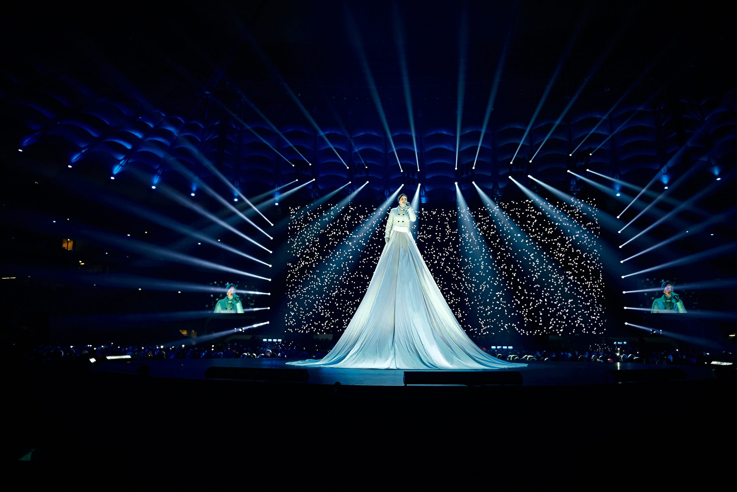 : A performer in a huge bright dress on a raised platform during a performance