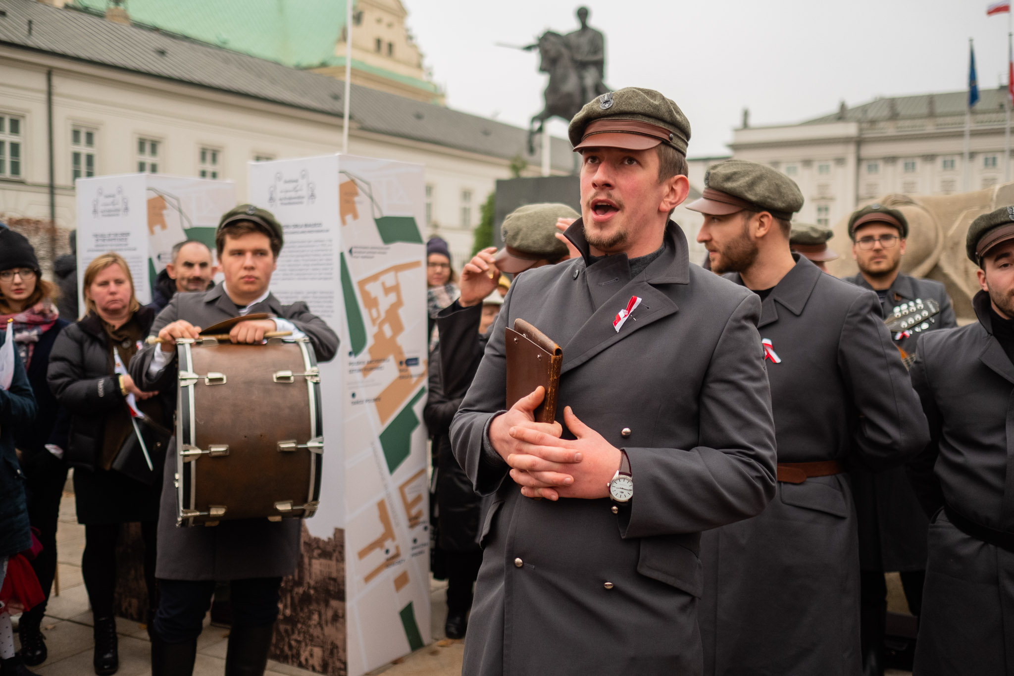 A group of musicians in identical stylised military uniforms during a performance in an urban space