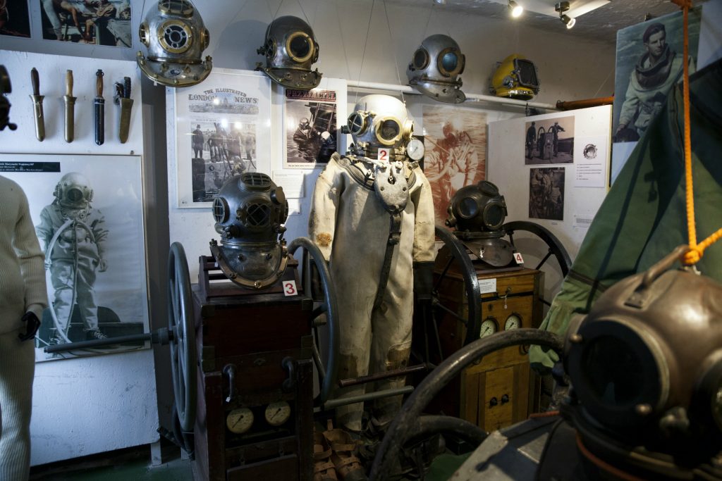 Historia nurkowania przedstawiona poprzez stroje nurków - zdjęcie przedstawia ekspozycję z dawnymi strojami nurków