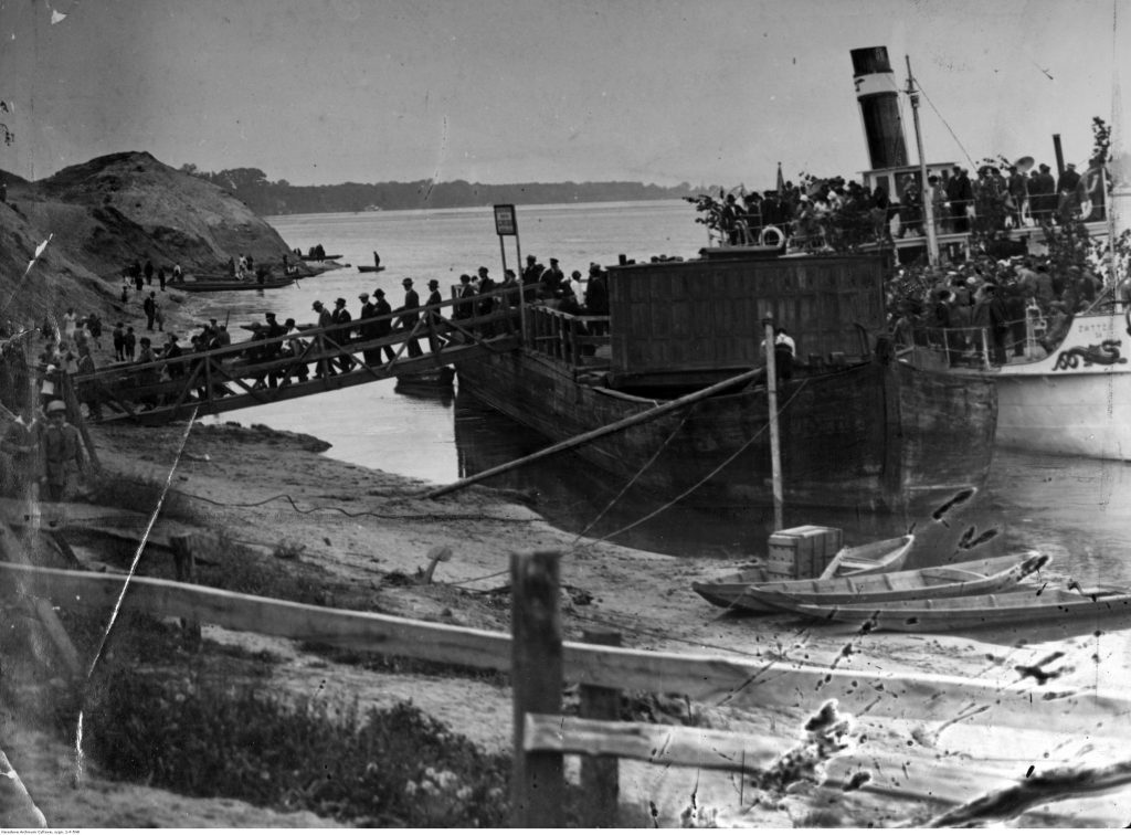 pochylony statek pełen ludzi z którego wąskim trapem wysiadają pasażerowie