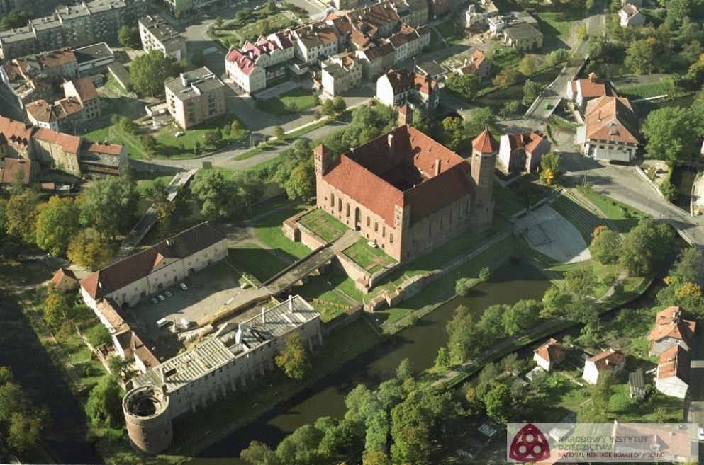 widok na dachy kwadratowego zamku z lotu ptaka, wokół tereny porośnięte drzewami