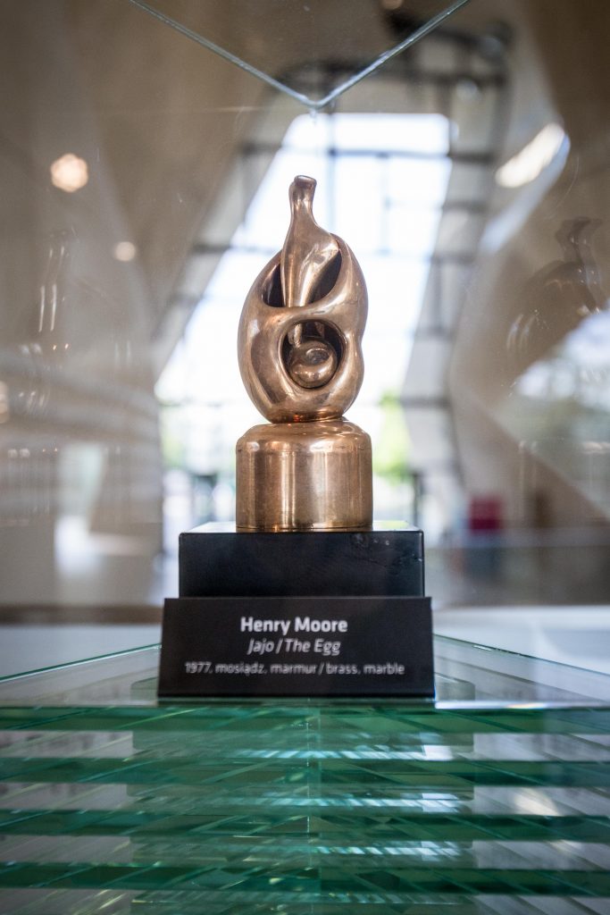 brązowy abstrakcyjny kształt jajowaty na czarnym postumencie z podpisem