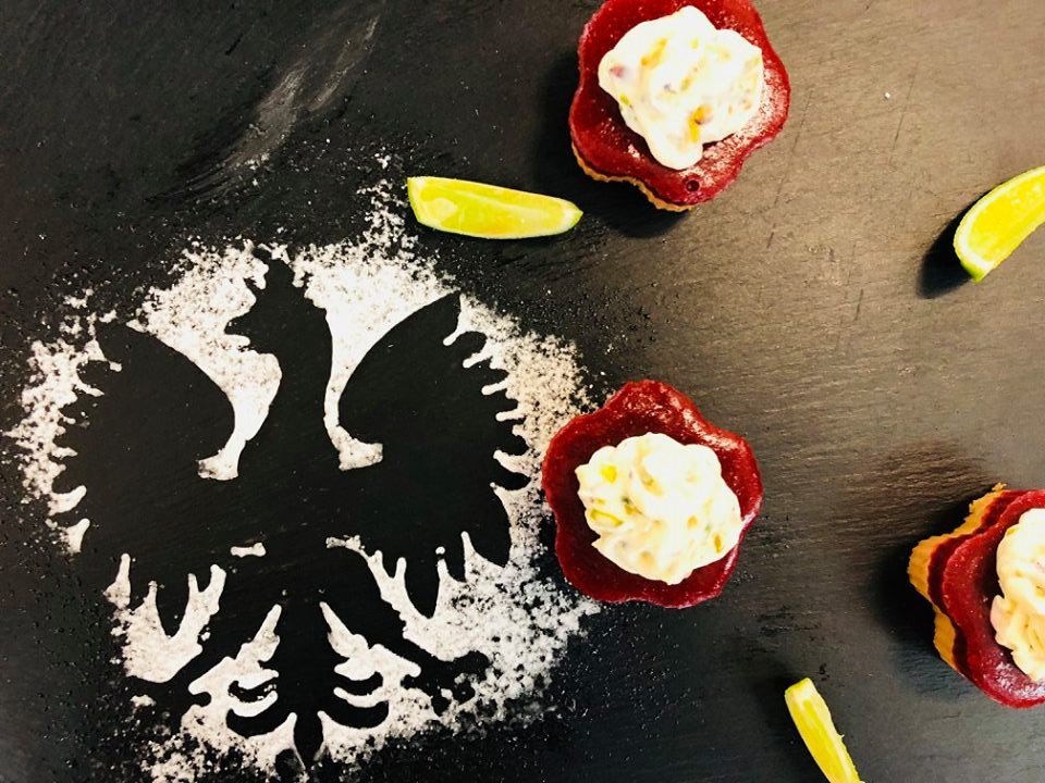 ciastka w kształcie kwiatów na czarnym blacie z orłem odsypanym z cukru-pudru i wśród cząstek cytryny