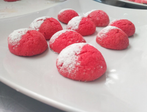 czerwone okrągłe ciasteczka, a ich połowa jest posypana cukrem-pudrem