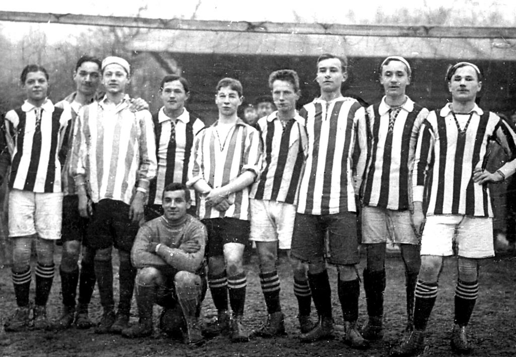 grupa dziesięciu mężczyzn w krótkich spodenkach i koszulach w biało-czarne paski