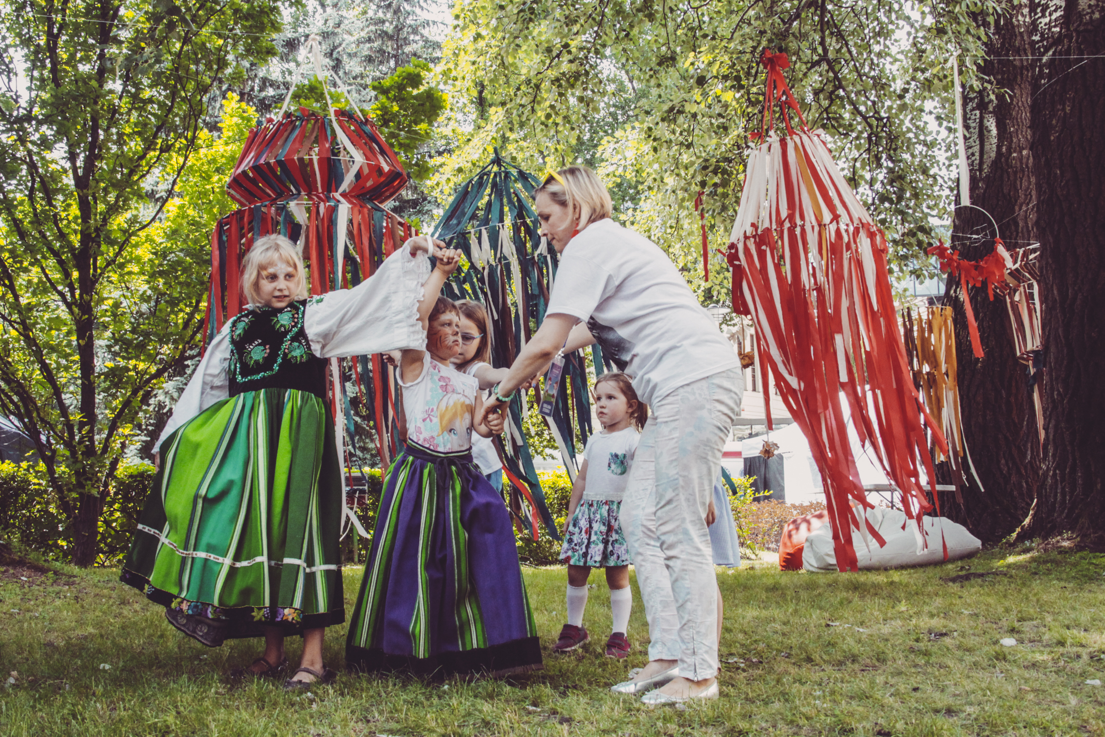 tańczące na trawie dziewczynki w strojach ludowych,
