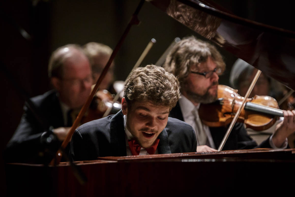 uśmiechnięty mężczyzna grający na fortepianie z epoki