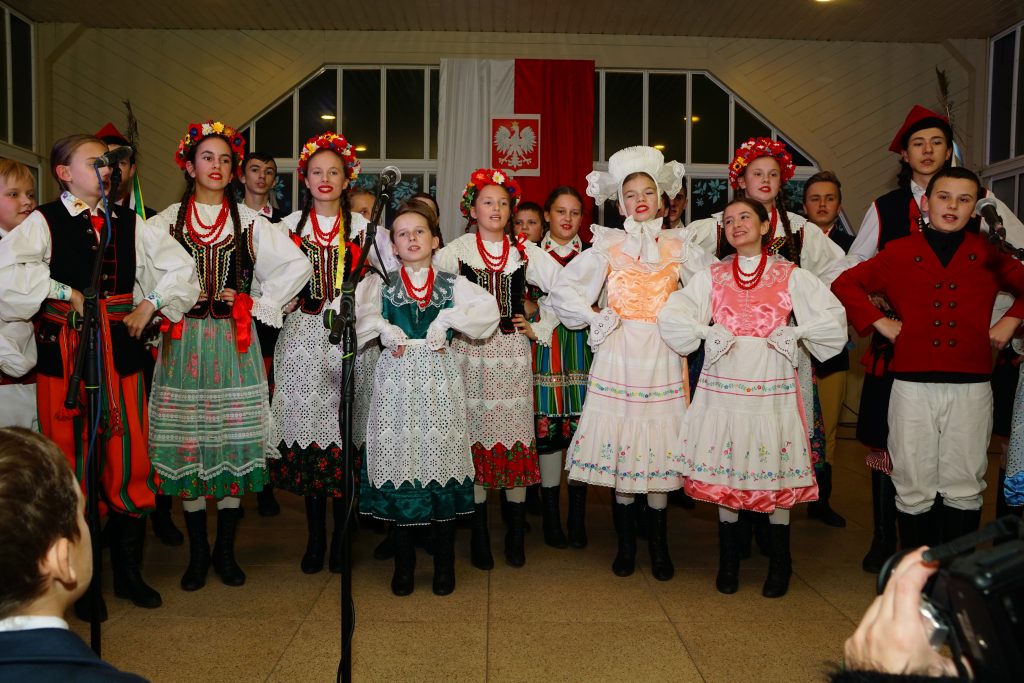 dzieci w strojach regionalnych śpiewają na scenie