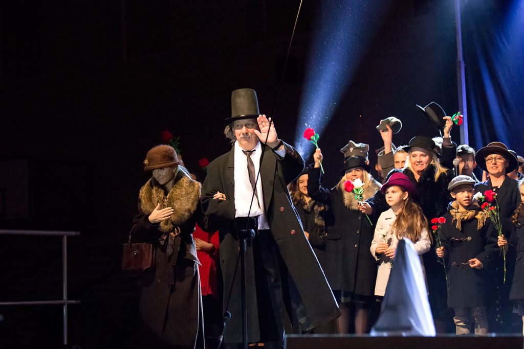 na zdjęciu aktor w przebraniu Paderewskiego z żoną wchodzą na scenę wśród wwatującego tłumu z kwiatami