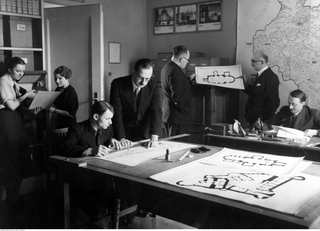 ludzie w biurze, rozłożone plany budynków