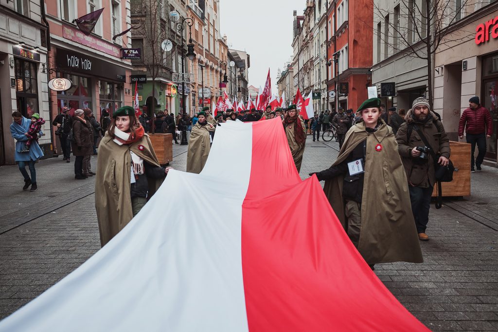 harcerki niosące długą flagę, w tle ludzie z flagami
