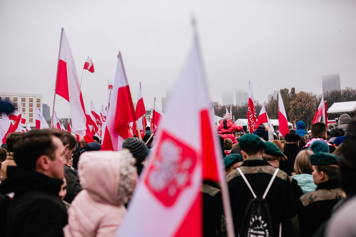 tłum ludzi maszerujący z biało-czerwonymi flagami