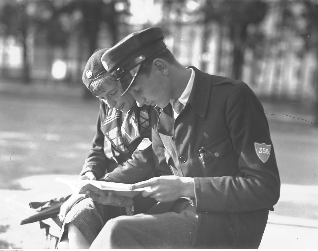 Uczeń i uczennica gimnazjum ubrani w nowe mundurki podczas lektury książki, 1933, fot. NAC