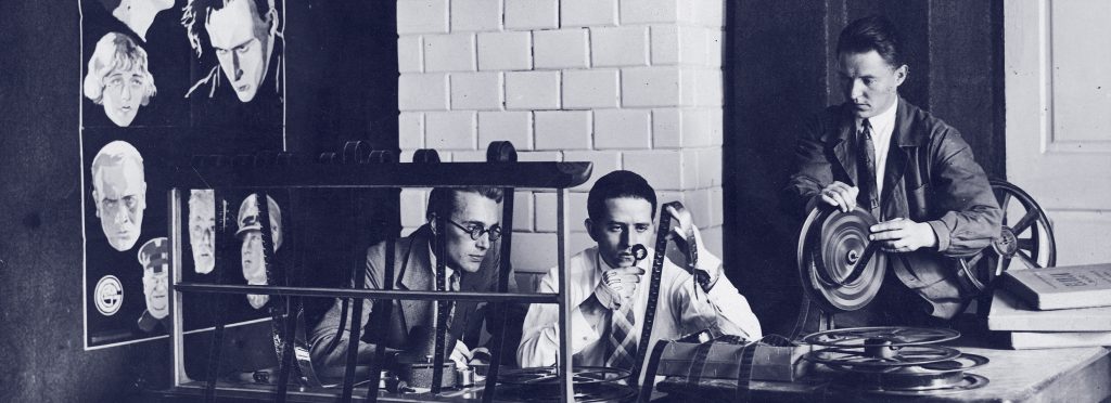 mężczyźni w pracowni przy biurku przeglądający klisze