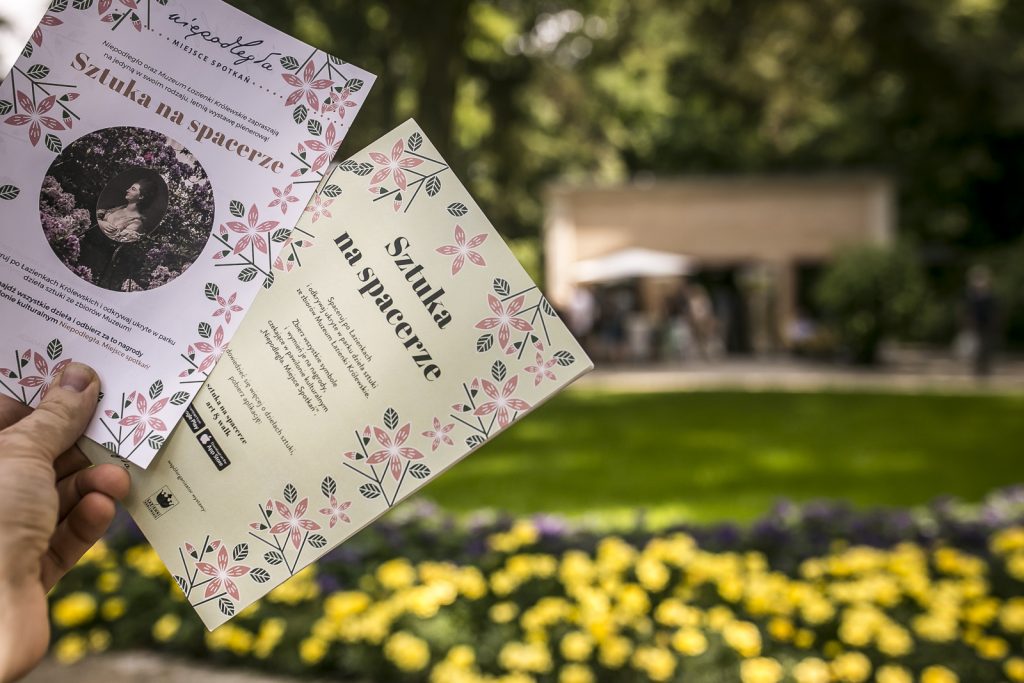 dwie ulotki z napisem "Sztuka na spacerze", w tle zamazany pawilon Niepodległa Miejsce Spotkań