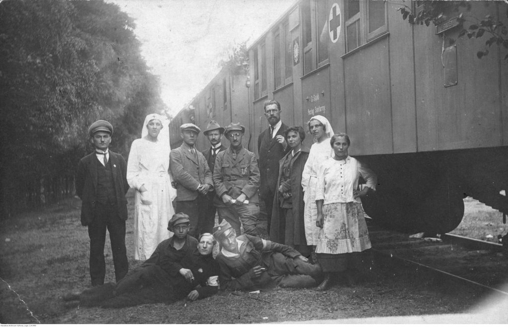 grupa mężczyzn i sanitariuszek pozuje przed pociągiem sanitarnym