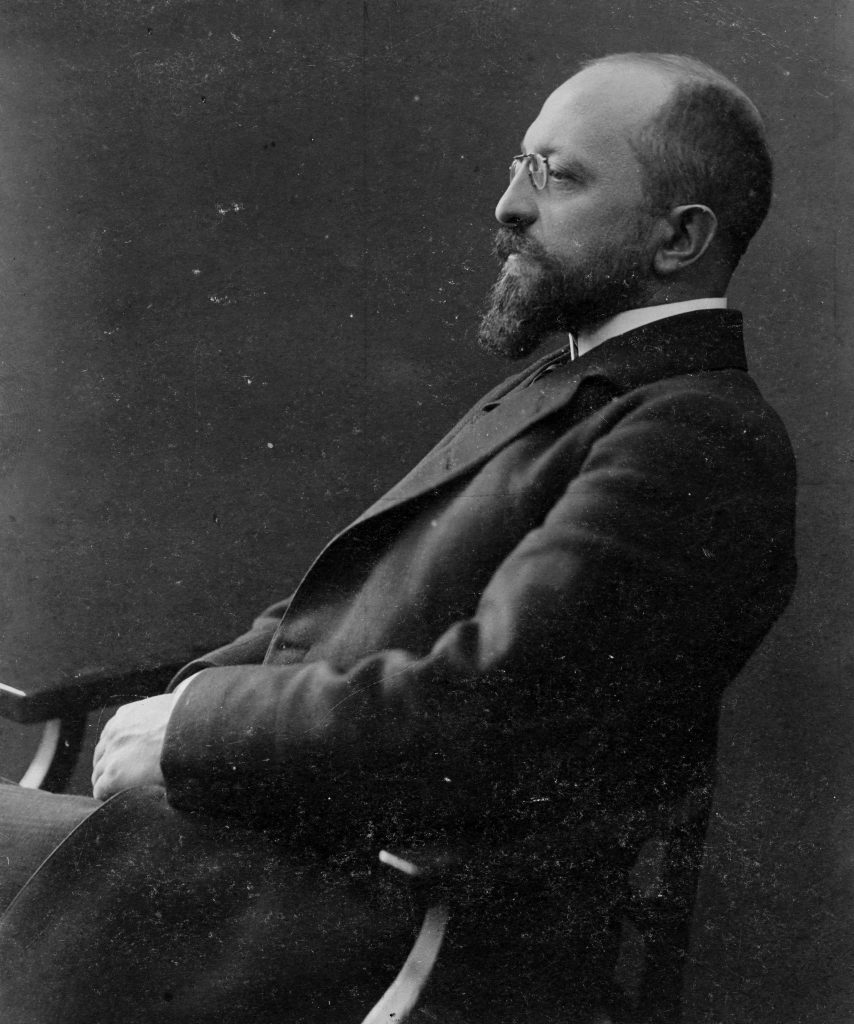 czarno-białe zdjęcie przedstawiające siedzącego na krześle mężczyznę