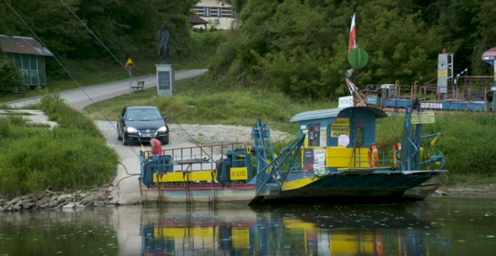 prom na rzecze przy brzegu do którego zbliża się samochód