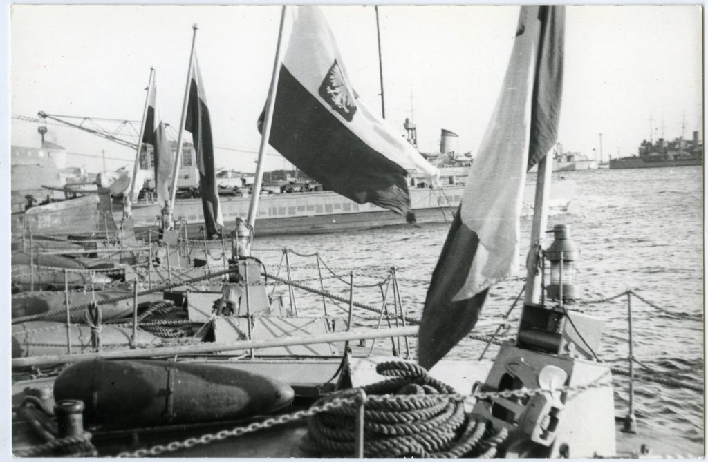 cztery polskie bandery na zacumowanych obok siebie w porcie okrętach