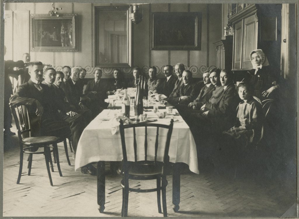 grupa ludzi siedząca wokół ozdobnie zastawionego stołu