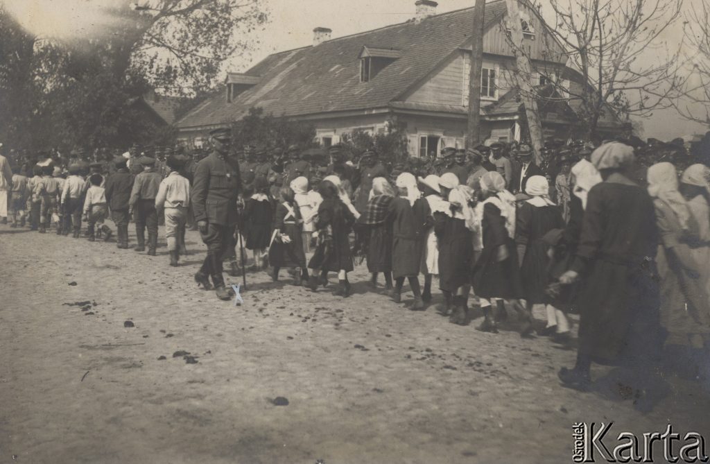 pochód ładnie ubranych dzieci na ulicy, w tle budynek