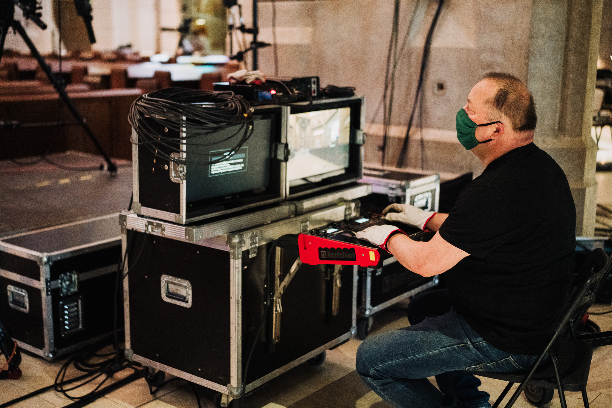 operator kamery przed swoim pulpitem w rękawiczkach i z maseczką na twarzy