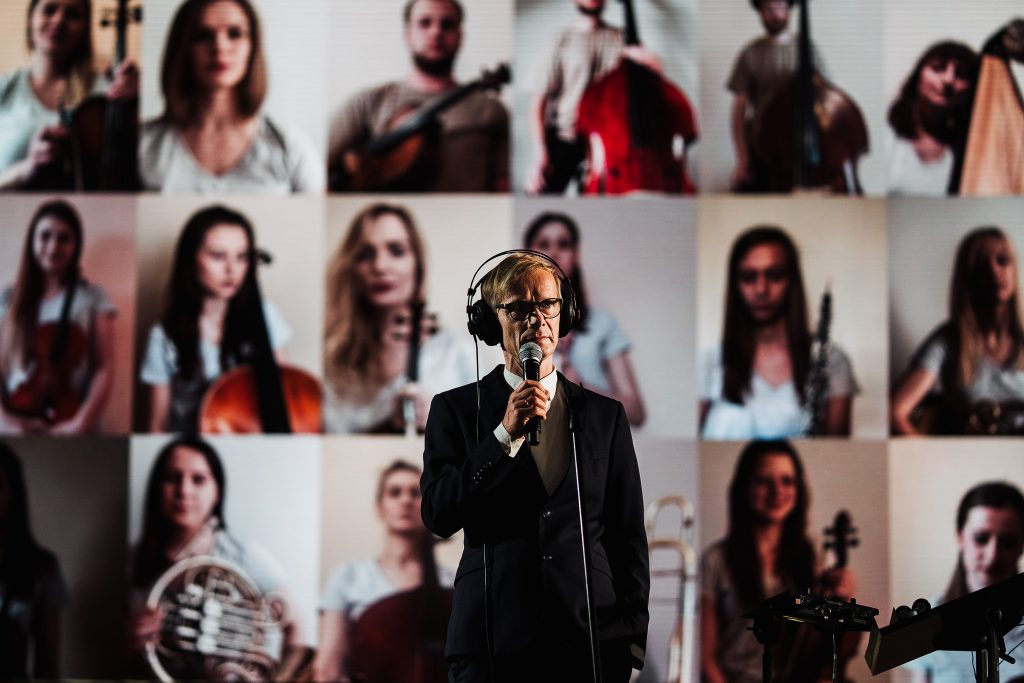 syrygent na scenie, w tle telebim z innymi wykonawcami