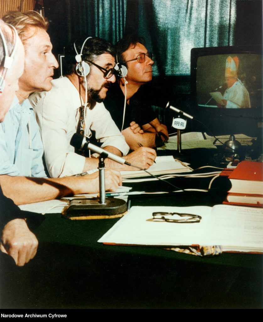 Widoczni od lewej: ksiądz Tadeusz Kirschke, Tadeusz Nowakowski, Andrzej Krzeczunowicz, Jerzy Kaniewicz. W tle odbiornik telewizyjny (telewizor). 