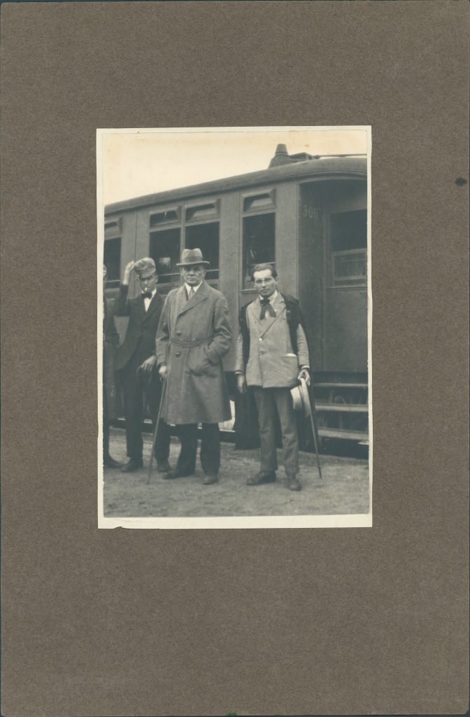 3 mężczyzn przed wagonem kolejowym