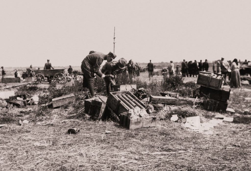 polscy żołnierze pochylający się nad skrzynkami z amunicją w polu