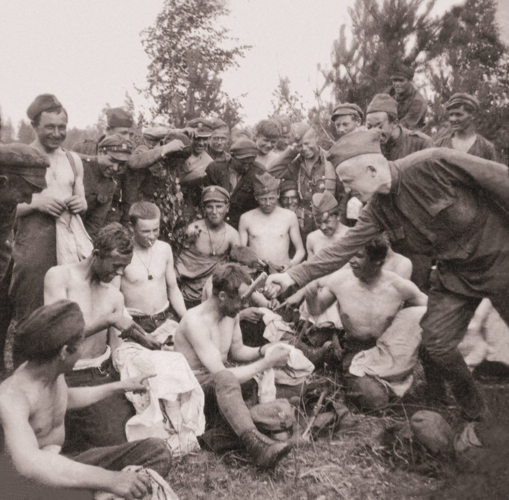 żołnierze uśmiechnięci i półnadzy podczas odpoczynku jeden z nich celuje w kolegę z pistoletu