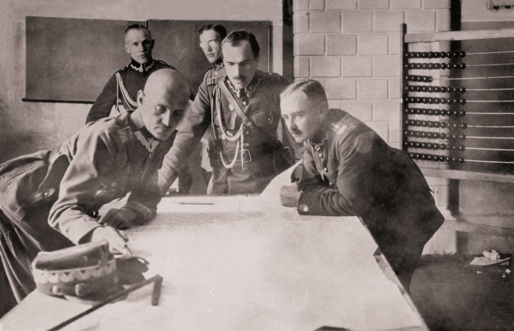 trzech mężczyzn pochylionych nad mapą na stole