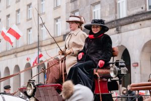 dwie kobiety w strojach retro w powozie z epoki, w tle budynek