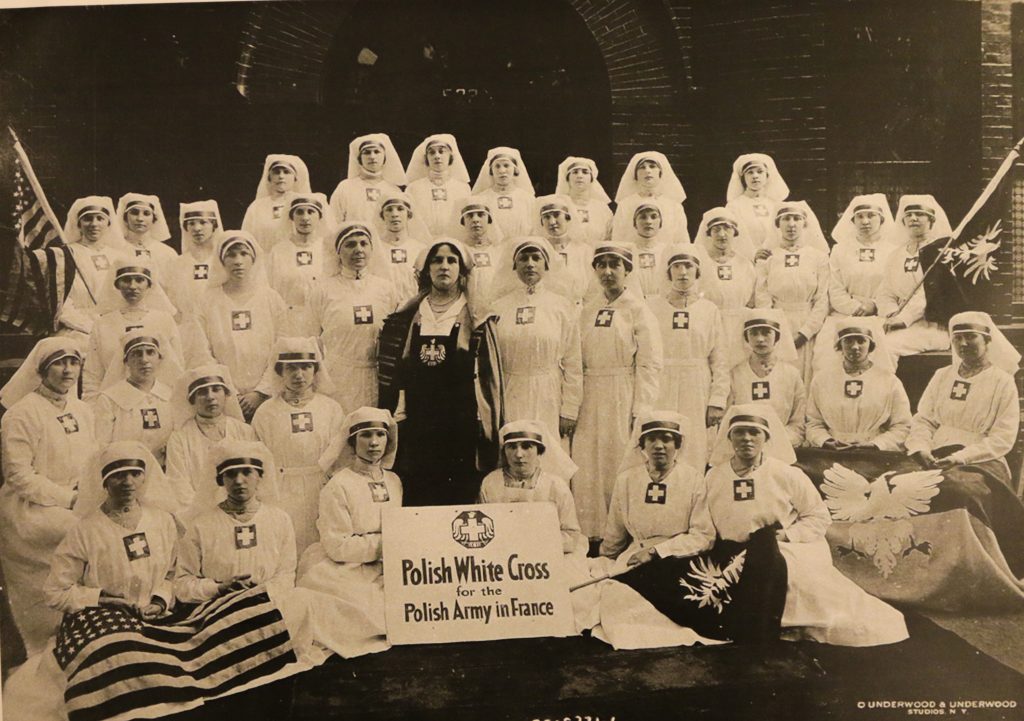 zdjcie grupowe kobiet, większość ubrana na biało, w środku na czarko Helena Paderewska. Sanitariuszki trzymają transparent z napisem po angielsku