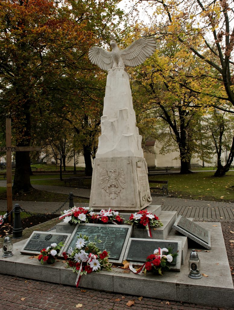 widok na pomnik złożony z elementów dwóch pomników - cokołu z pierwszego, i częśći artystycznej z orłem z drugiego. Wokół, u stóp różne tablice i złożone kwiaty