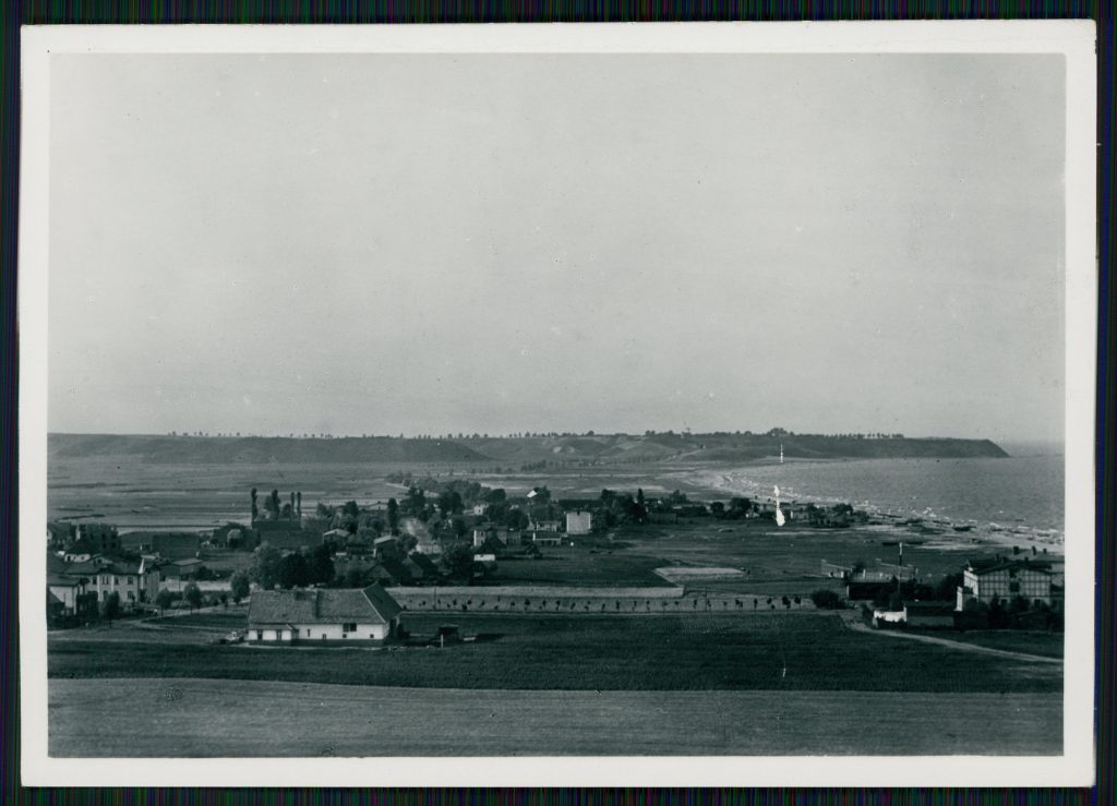 widok na płaski teren z radkimi zabudowaniami i morze