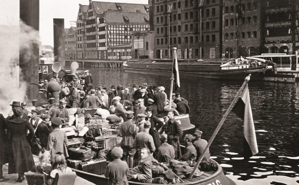 ludzie na łódce na rzece, w tle spichrze gdańskie