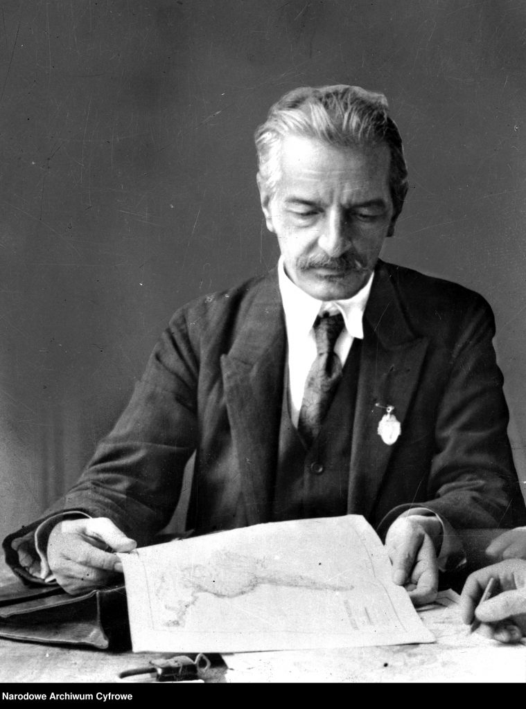 mężczyzna w garniturze, trzyma w rękach mapę