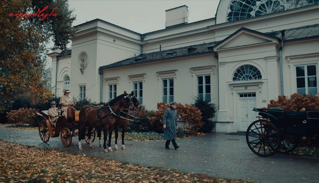 przed eleganskim budynkiem zaparkowane są dwa powozy, Piłsudski idzie do wejścia