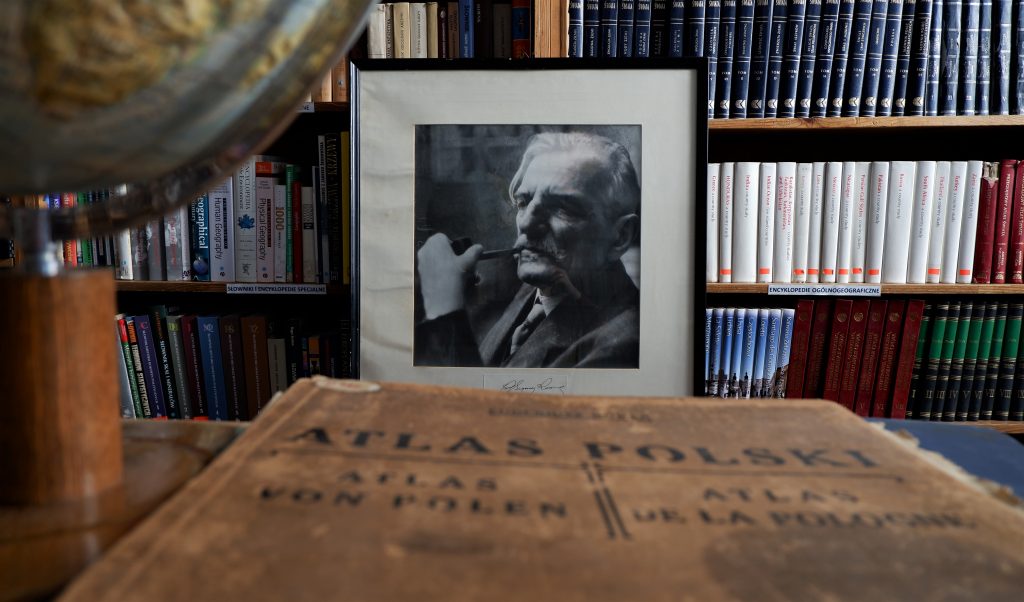 na pierwszym planie Atlas Polski z 1916 roku, w tle czarno-biały portret Romera