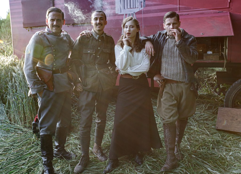 czwórka aktorow przed wozem fotograficznym - elementem scenografii filmowej