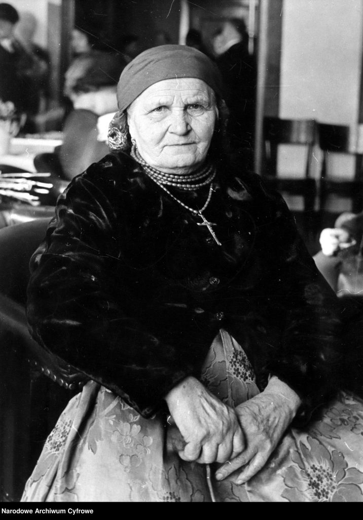 zdjęcie portretowe siedzącej starszej kobiety w śląskim stroju ludowym z krzyżem na piersi