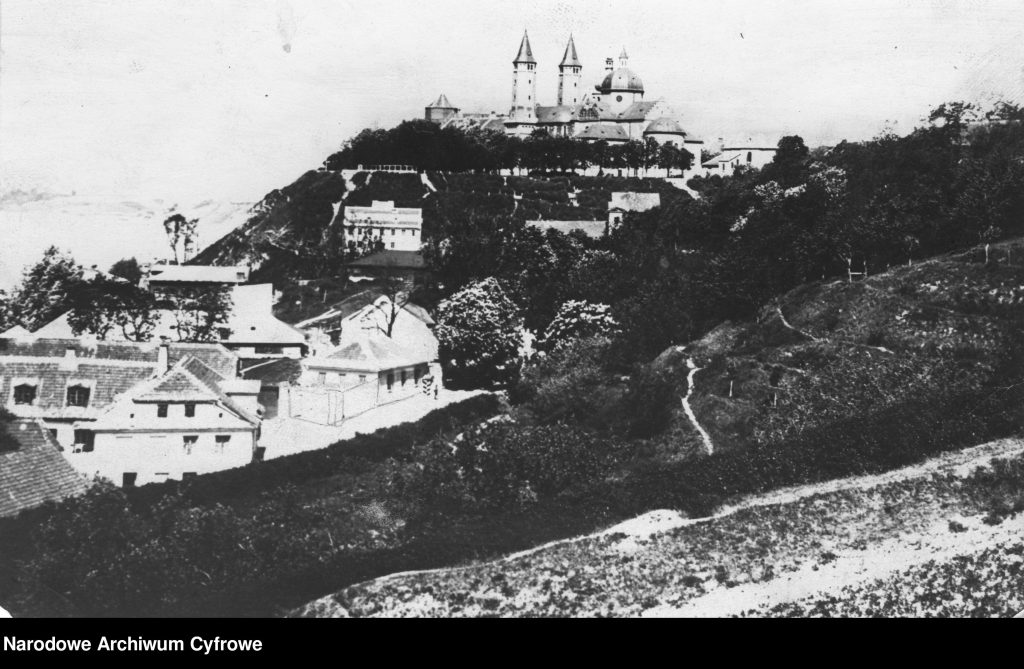 widok na okazały kościół na wzgórzu, po prafej dachy zabudowy miejskiej