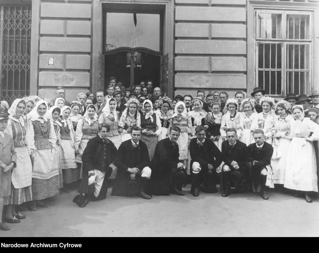 zdjęcie grupowe, młodzi w ludowych strojach pozują przed budynkiem