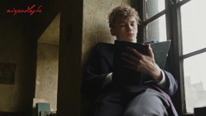 chłopak na parapecie okna czyta Pana Tadeusza trzymanego w rękach