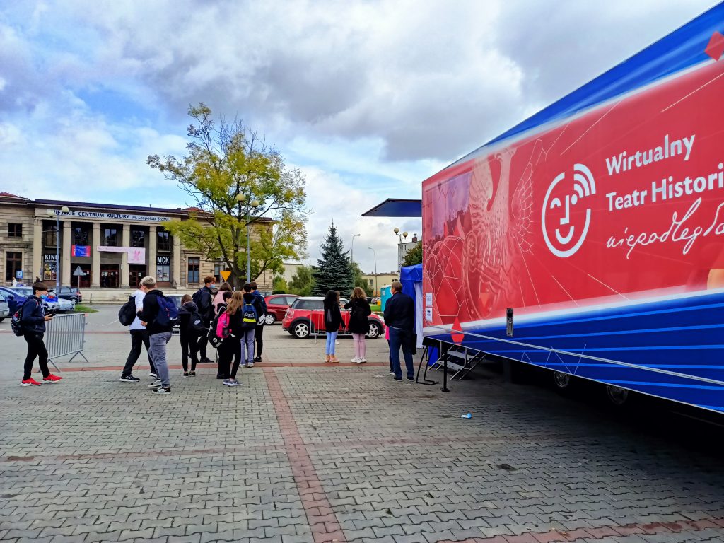 na pierwszym planie tir WTH, przed wejściem grupki dzieciaków, w tle gminne centrum kultury