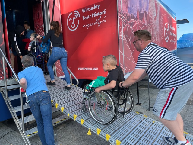 wjazd osób na wózkach inwalidzkich do ciężarówki z wystawą 