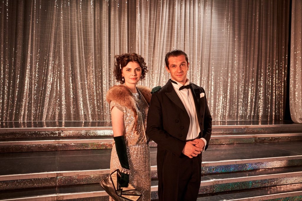 kobieta i mężczyzna w modnych międzywojennych strojach pozuje na tle kurtyny
