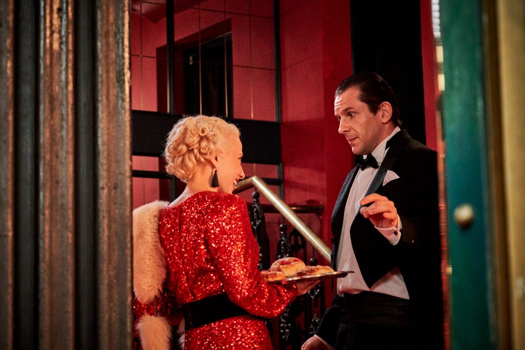 kobieta prezentuje tacę z słodkimi przekąskami zaskoczonemu mężczyźnie we fraku