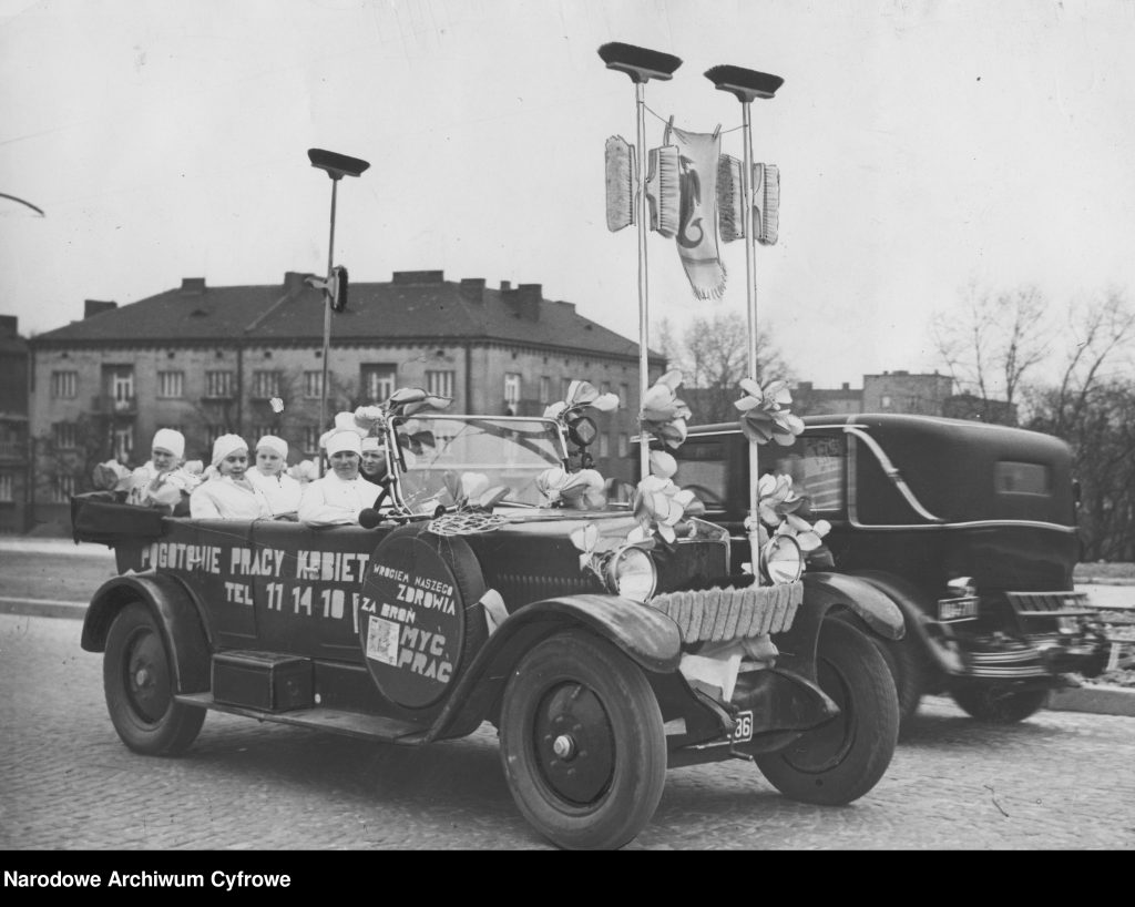 samochód z kobietami na ulicy Warszawy, na boku auta hasło promocyjne